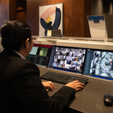 Image of a concierge sitting behind a desk watching security screens