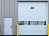 White garage roller door with yellow bollards at the side